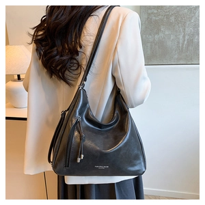 Detailed view of black crescent leather shoulder bag with white fashion text and side zipper