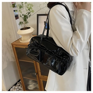 Macro shot of black patent leather bowling bag with vintage bow detail and glossy finish