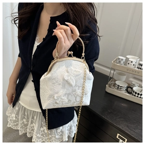 Detail of white lace clutch bag with butterfly embroidery and golden metal frame