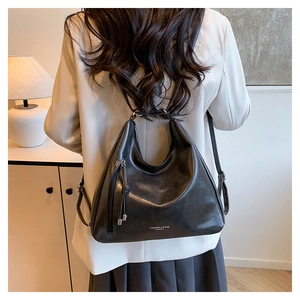 Detail of black glossy PU leather backpack with tassel zipper and silver hardware