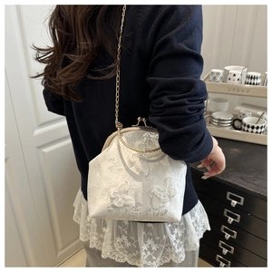 Detail of white lace handbag with butterfly appliques and round gold metal handles