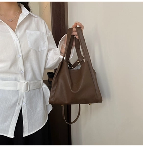 Detail of dark brown pebble leather tote bag with gold protective base feet and strap