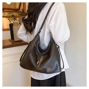 Detail of dark coffee tote bag featuring soft matte leather and metal tassel zipper