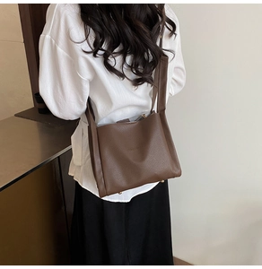Detailed macro view of caramel lychee grain leather texture and golden bottom studs on tote bag