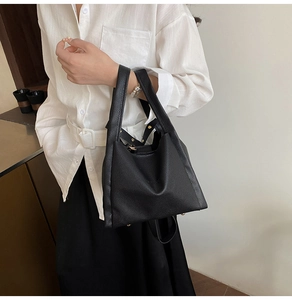 Detail of black lychee grain leather bucket bag with metal bottom studs and wide handles