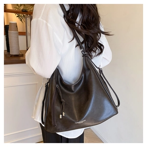 Detail view of large brown PU leather tote bag with side zipper and metal ball pendant