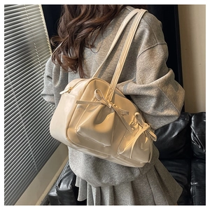 Detail van een beige PU-leren draagtas met stijlvolle strikzakken en glanzende afwerking