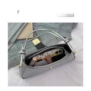 Détail d'un sac à bandoulière argenté montrant l'espace pour téléphone et cosmétiques