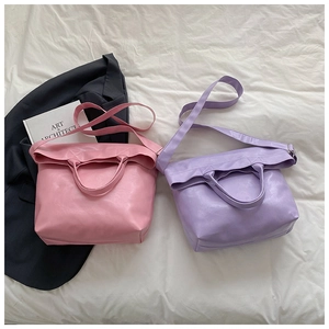 Flat lay detail of pink and lilac soft leather tote bags on white fabric background