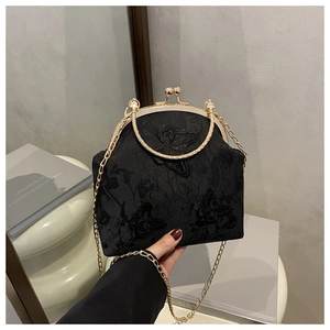 Detailed close-up of butterfly embroidery and vintage golden clasp on black lace handbag
