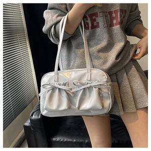Detail of light grey patent leather shoulder bag featuring decorative ribbon bows