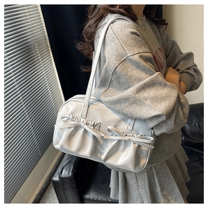 Borsa a spalla argento metallizzato con tasche a fiocco e manici lunghi indossata da modella
