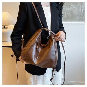 Detail view of large brown vintage leather tote bag with metal zipper and long strap