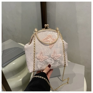 Detailed macro of pink lace handbag featuring 3D butterfly embroidery and gold metal clasp