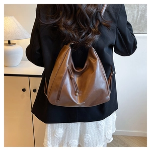 Detail of caramel brown PU leather tote bag with decorative zipper and white brand text