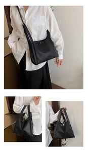 Detail of black lychee grain leather bucket bag with top handles and adjustable strap