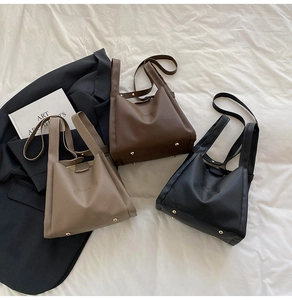 Detailed view of bucket bags in litchi grain leather with protective gold metal feet