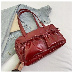 Dettaglio della borsa a spalla in pelle verniciata rosso scuro con tasche a fiocco e lucentezza