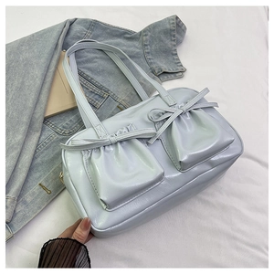 Dettaglio della borsa tote azzurra perlata con fiocchi decorativi e tasche a pieghe