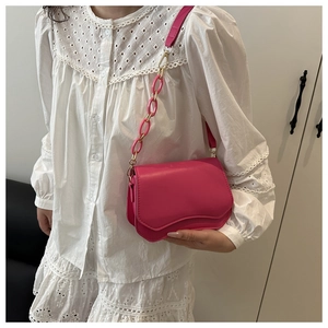 Detail of rose red crossbody bag with chunky chain strap and scalloped edge detail
