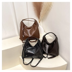 Close-up of three versatile leather tote bags in brown, black, and coffee on a white podium