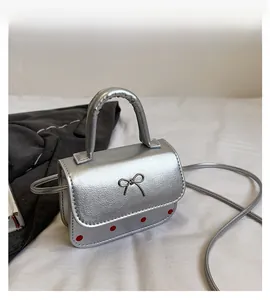 Détail du sac argenté avec nœud métallique et accents de points rouges