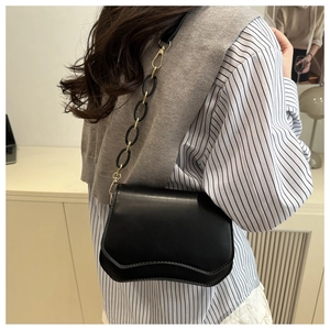 Minimalist black leather crossbody bag with wavy flap detail shown on a model