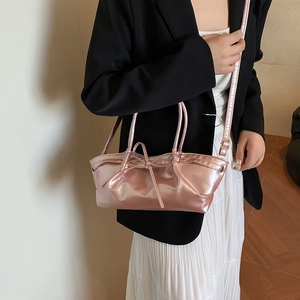 Sac fourre-tout rose métallisé avec nœud, porté par un mannequin en jupe blanche