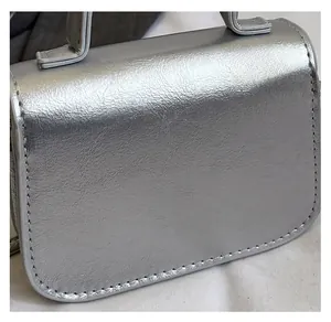 Gros plan sur le cuir PU argenté avec coutures blanches sur le sac à main tendance