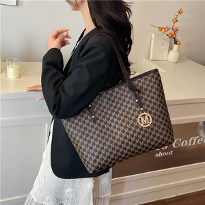 Large capacity monogram tote bag with gold M logo pendant worn over the shoulder