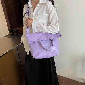 Lavender soft leather tote bag with adjustable shoulder strap shown on a female model