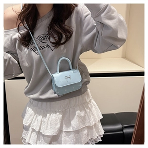 Détail du mini sac bandoulière bleu clair avec nœud métallique et motif à pois blancs