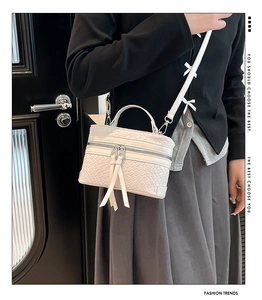 Close-up of white woven camera bag with cute bow accents and silver double zippers
