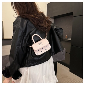 Close-up of pink crossbody bag with silver bow and black polka dots on model