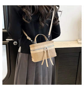 Detail of beige woven texture bag with long tassels and adjustable shoulder strap