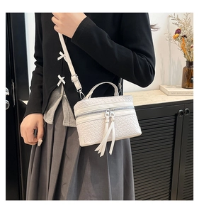 Detailed view of a white woven box bag with adjustable crossbody strap and dual metal zippers