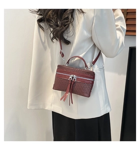 Detail der weinroten Webstruktur-Box-Tasche mit Fransenquaste und silbernem Zipper