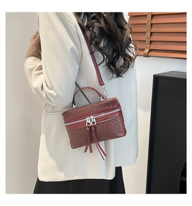 Detailansicht der rotbraunen Eimertasche mit Webmuster und Fransen an einem Modell