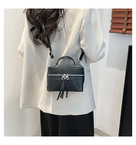 Detail einer schwarzen Eimertasche mit Webmuster, Silberbeschlägen und Lederquasten