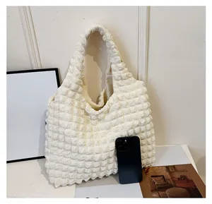 Size comparison of an off-white popcorn texture tote bag with a smartphone and magazines