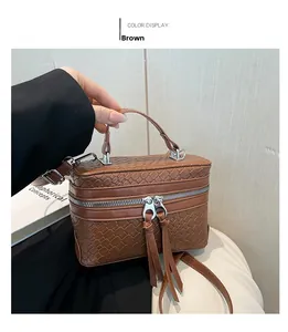 Detail einer braunen handgewebten Tasche mit Reißverschluss und doppelten Quasten