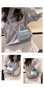 Mini sac bandoulière bleu clair à pois avec nœud argenté porté par le mannequin