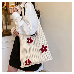 Détail du sac cabas en crochet crème avec motif floral rouge et texture tricotée