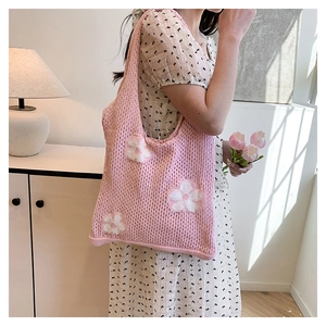 Close-up of pink knit tote bag featuring white floral patterns and openwork texture