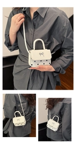Détail du mini sac blanc à pois noirs avec fermoir papillon argenté et bandoulière fine