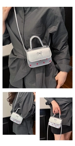 Détail du mini sac bandoulière argenté avec base à pois rouges et accent nœud métallique