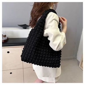 Detail of black pleated popcorn texture on oversized nylon tote bag worn by model