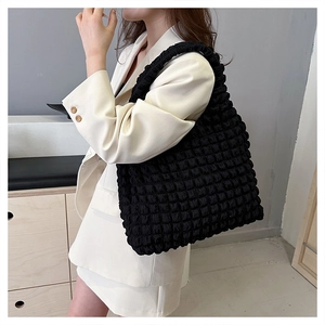 Detail of black pleated cloud tote bag showing bubble texture and spacious nylon design