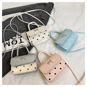 Disposition détaillée de quatre mini sacs à main à pois avec boucles métalliques sur un lit