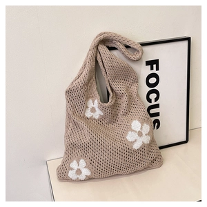Close-up of knit tote bag featuring hollow texture and white floral pattern details